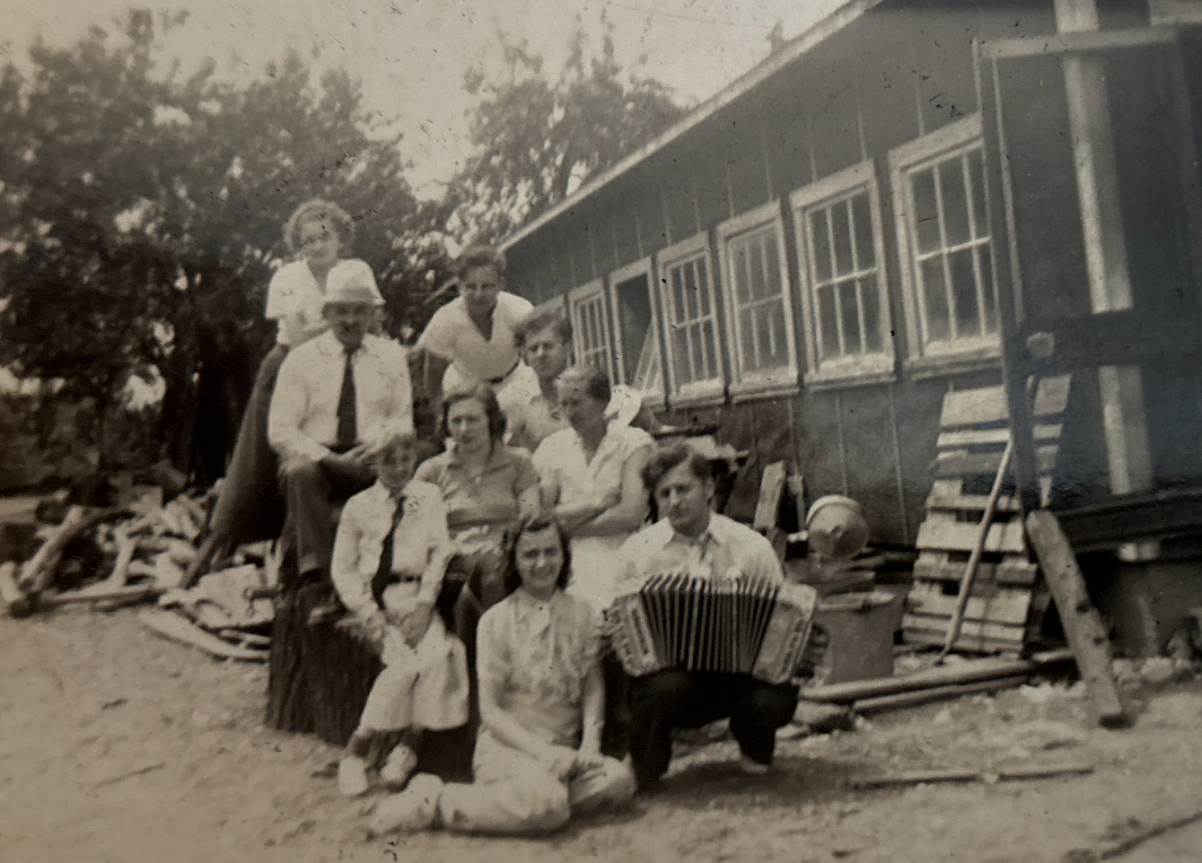 (Black and white) A family of nine posing, one man in the front holding a Chemnitzer.